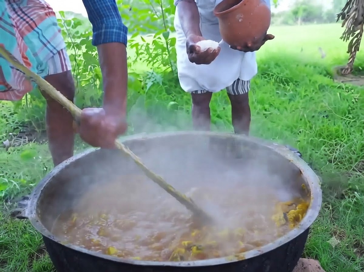 大きな鉄鍋の中の湯気の立つ混合物の上から、素焼きの壺から白いクリスタルソルトを注いでいる人。