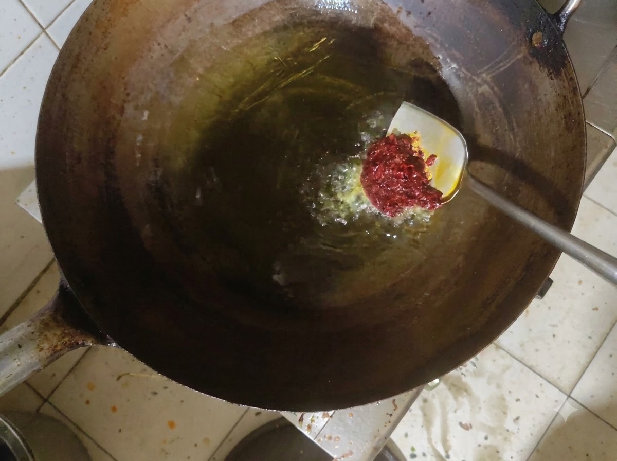中華鍋の熱した油の中で豆板醤が炒められている様子。