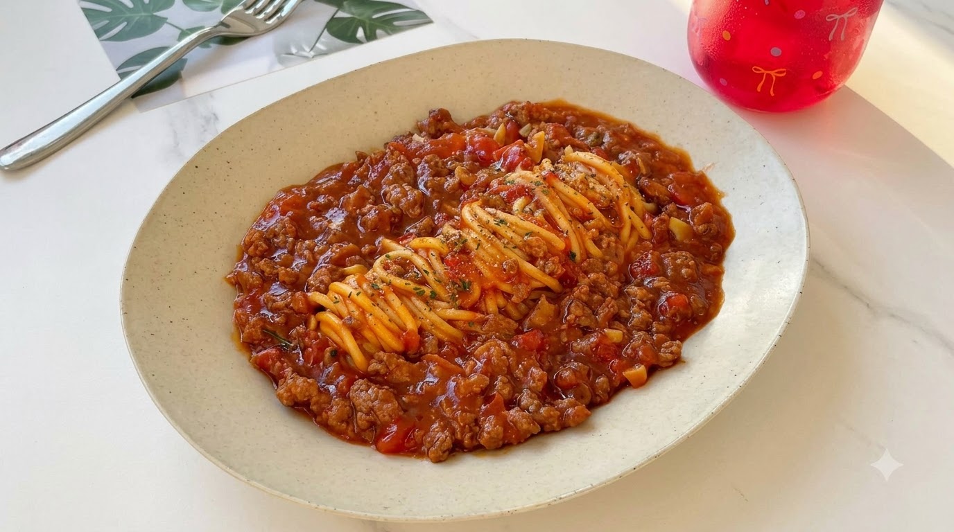 刻みパセリと粗びき黒こしょうをトッピングした、旨味あふれるトマトビーフパスタの皿