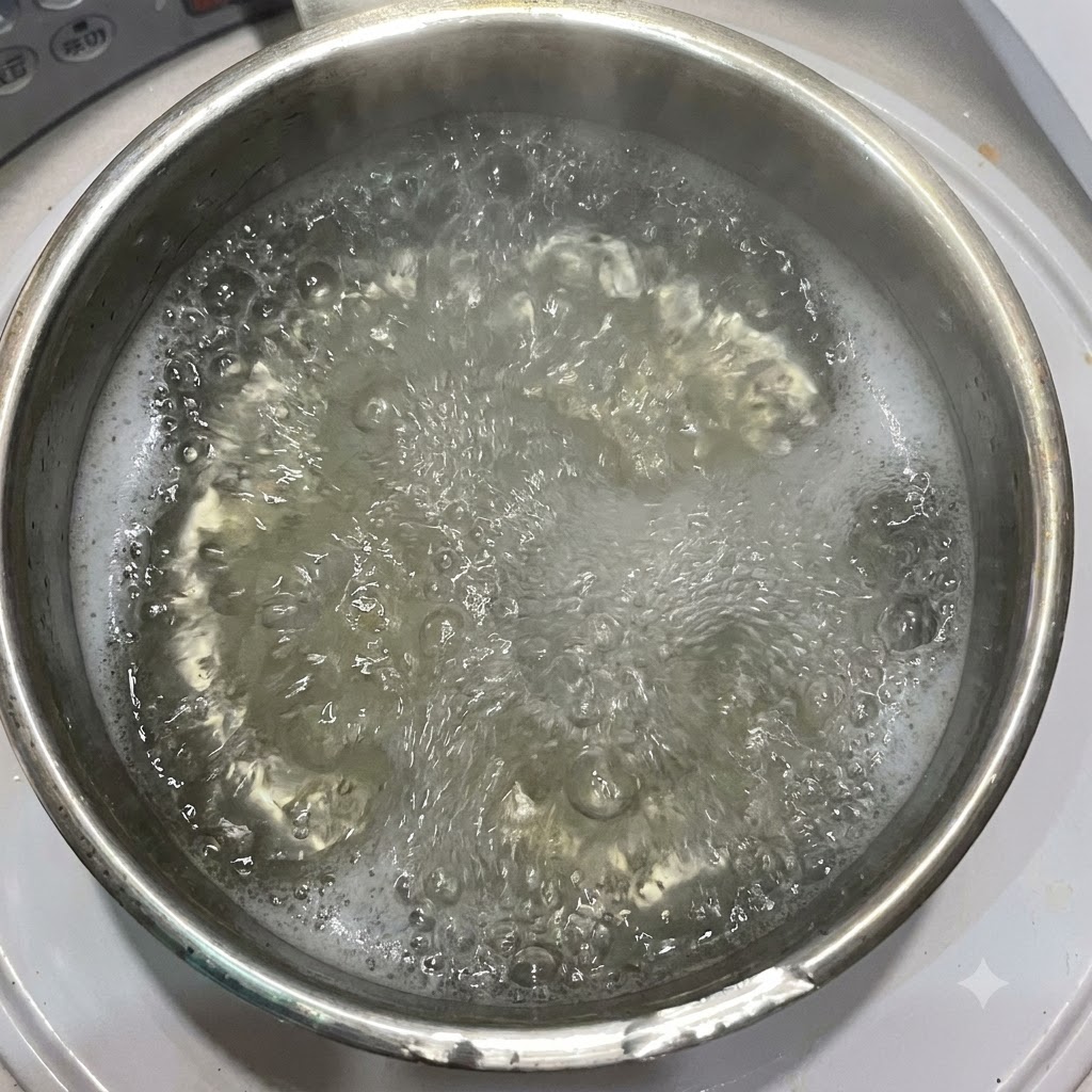 ペンネパスタが入った沸騰したお湯の鍋に、オリーブオイルが注がれている様子。