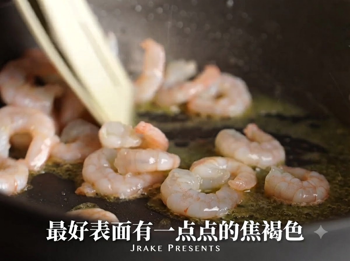 オイルの入ったフライパンでエビが焼け、ピンク色に変わり表面が香ばしく色づいている様子。
