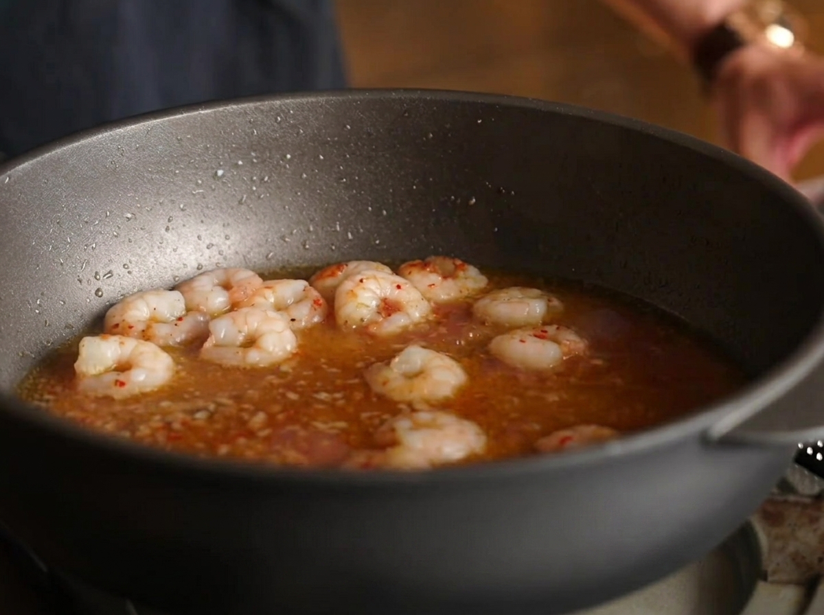 エビ、煮汁、ソースが入ったフライパンにスパゲッティの麺が和えられている様子。
