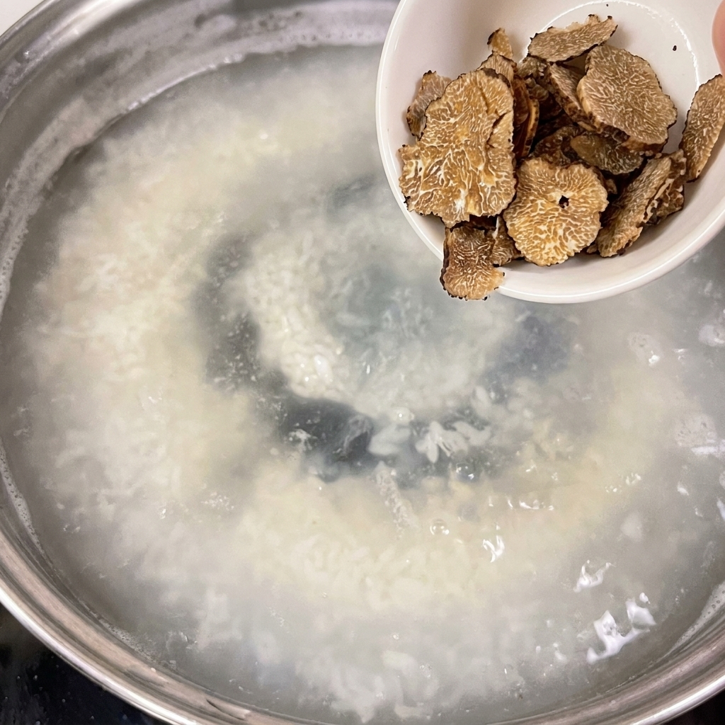 薄切りトリュフの入った小さな白い器から、沸騰した鍋に食材が入れられているところ。