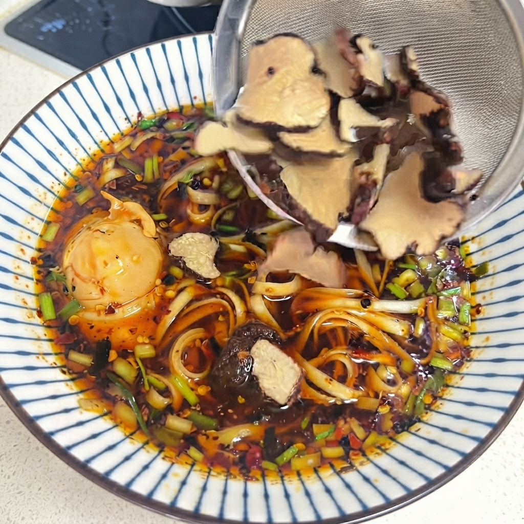 調理済みのトリュフスライスを乗せた、卵と刻みネギが入ったピリ辛麺の器。