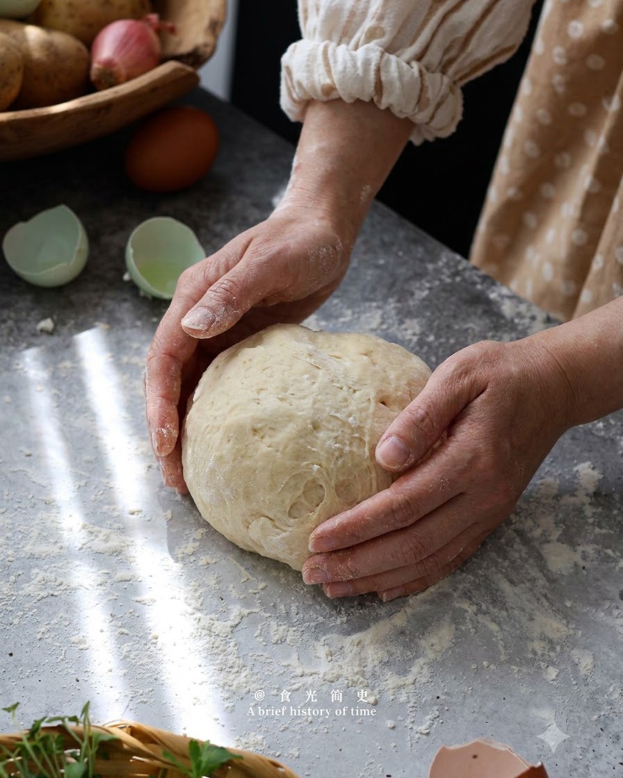 粉をふった作業台の上で、手で優しくポテトニョッキの生地を丸くまとめている様子。