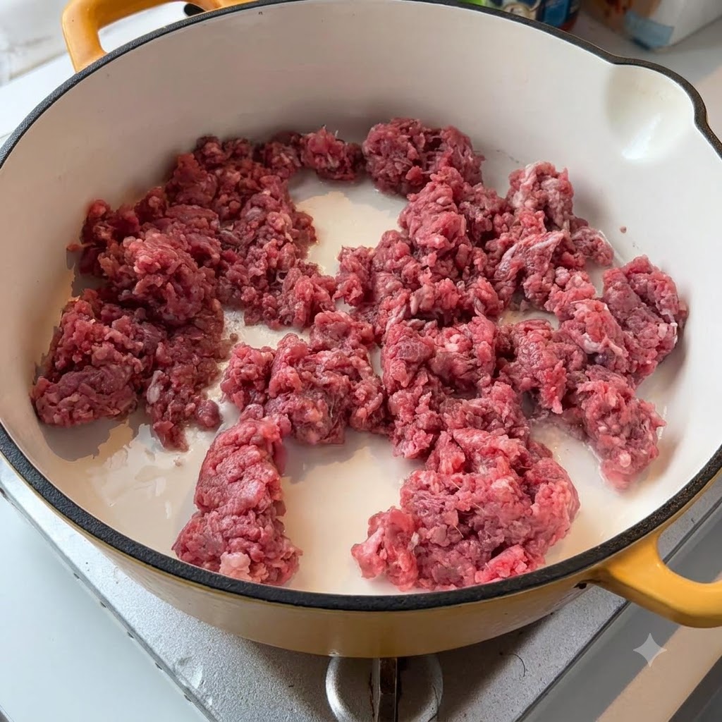 明るい色のフライパンの上で、生きた牛ひき肉と白タマネギがジュウジュウと炒められている状態。