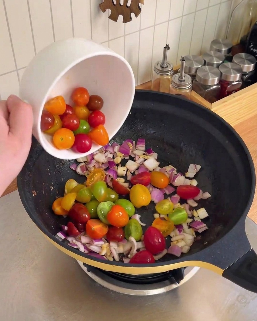 みじん切りにした赤玉ねぎとにんにくを中華鍋で炒めている様子。