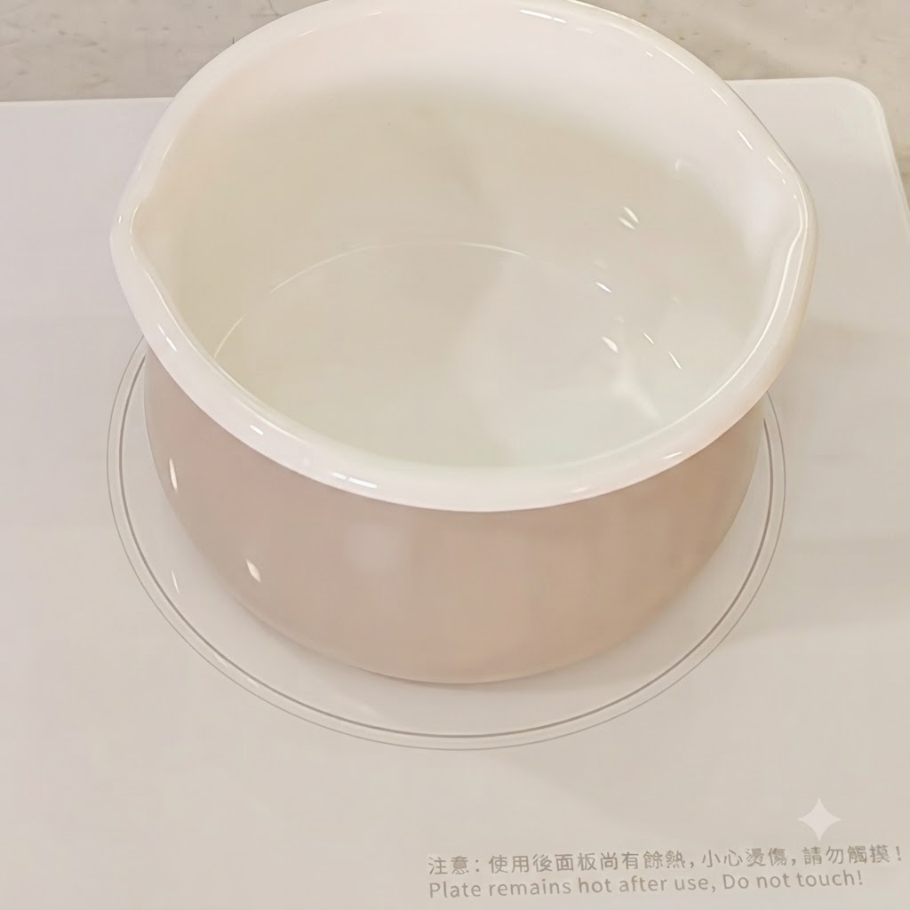 IHコンロの上の白い鍋に注がれる水。