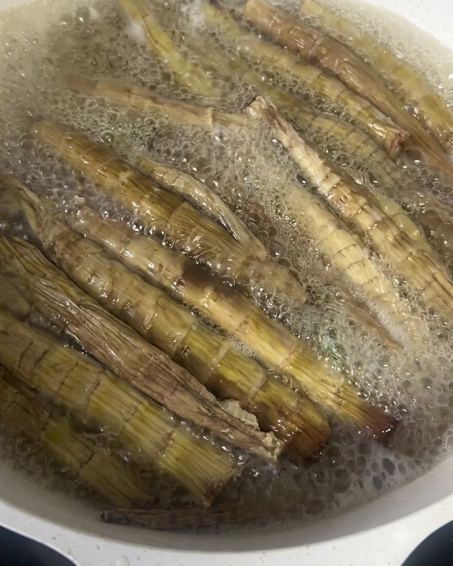 熱湯を入れた鍋の中で激しく泡立って茹でられる干しタケノコ。