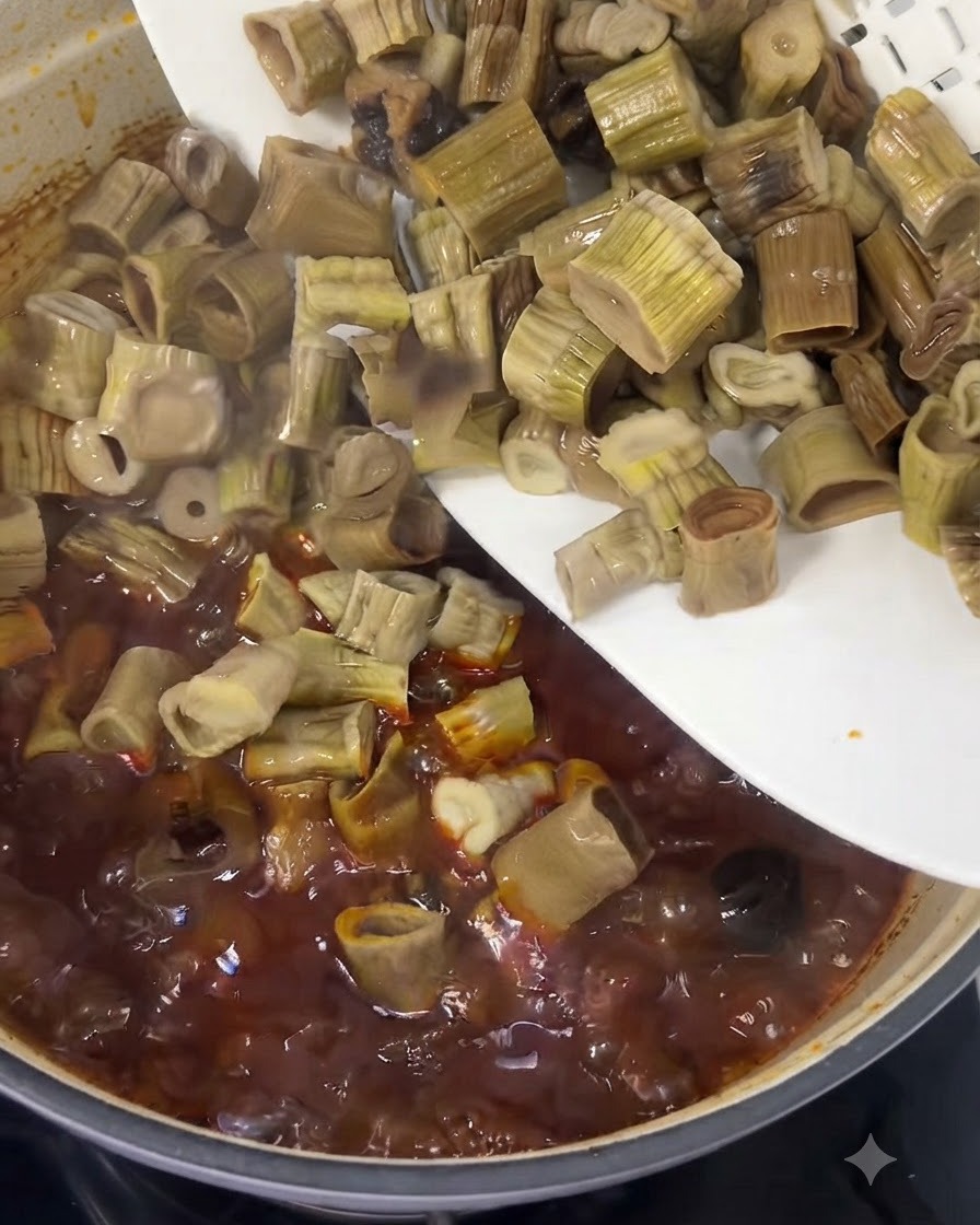 白い皿から刻んだタケノコが、グツグツと煮える赤い牛肉のシチューに滑り込ませる瞬間。