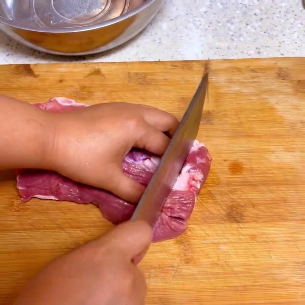 木製のまな板の上で、キッチンの包丁を生の牛肉を大きな塊にスライスしているところ。