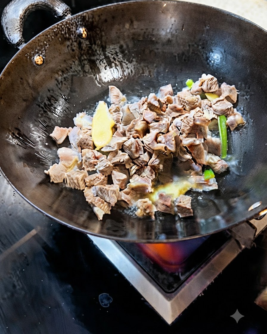 生姜と長ネギのスライスと一緒に、熱した中華鍋で下茹でした牛肉の角切りを炒めているところ。