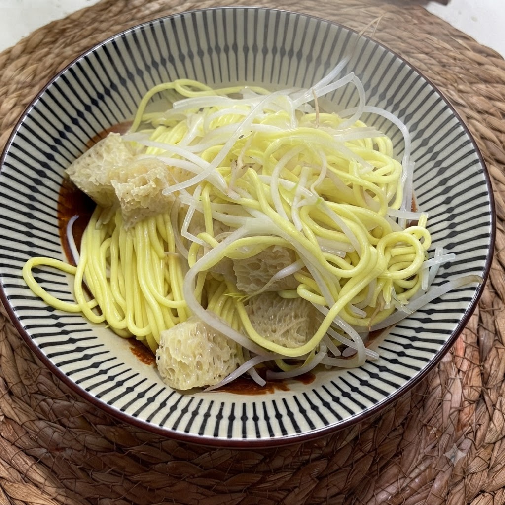 ボウルに入った茹でた中華麺の上に、白いもやしと細かく刻んだ漬物がトッピングされている様子。