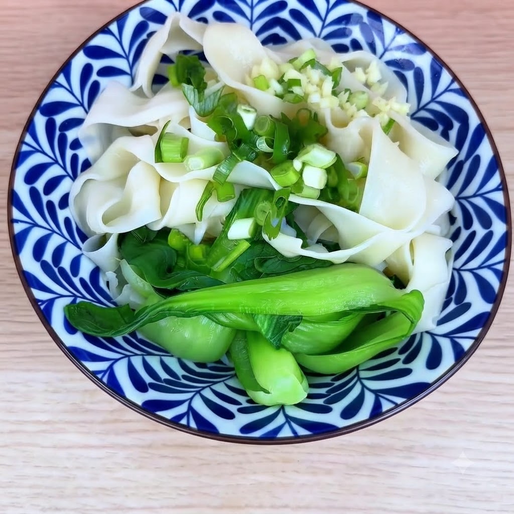 茹でた麺とチンゲン菜のうえに刻みネギとにんにくのみじん切りがトッピングされた状態。
