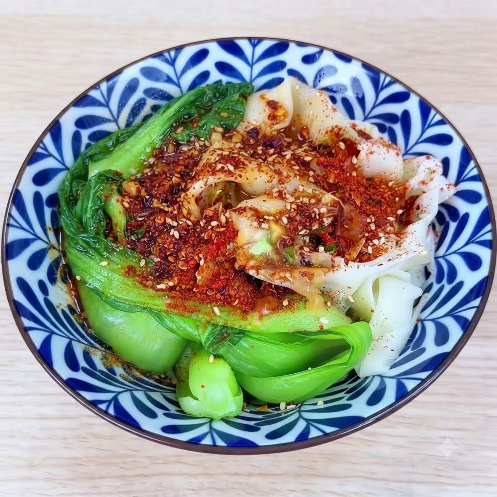 唐辛子と薬味の山に熱した油を注ぎ、ボウルの中でジュッと音を立てて香りが立っている様子。