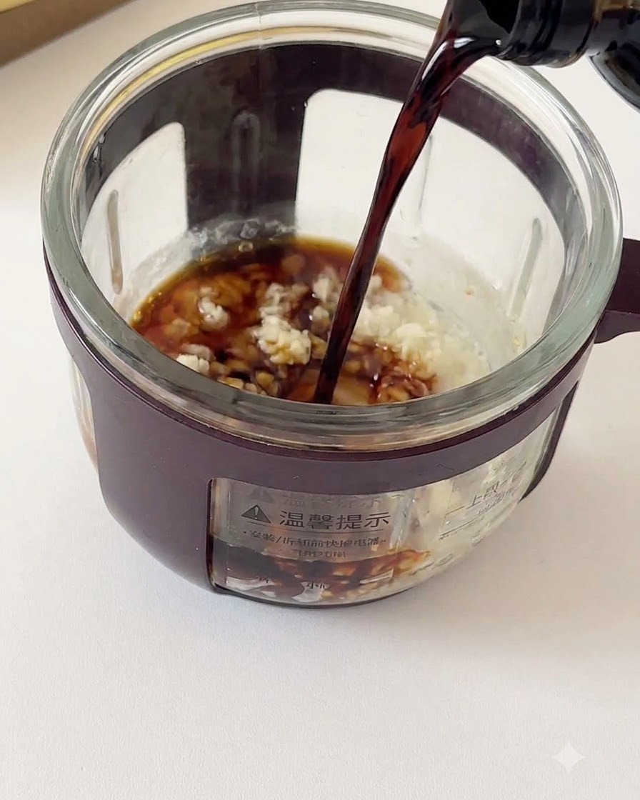 おろしにんにくや調味料が入ったガラス容器に、ボトルからダークソイソースが注がれている様子。