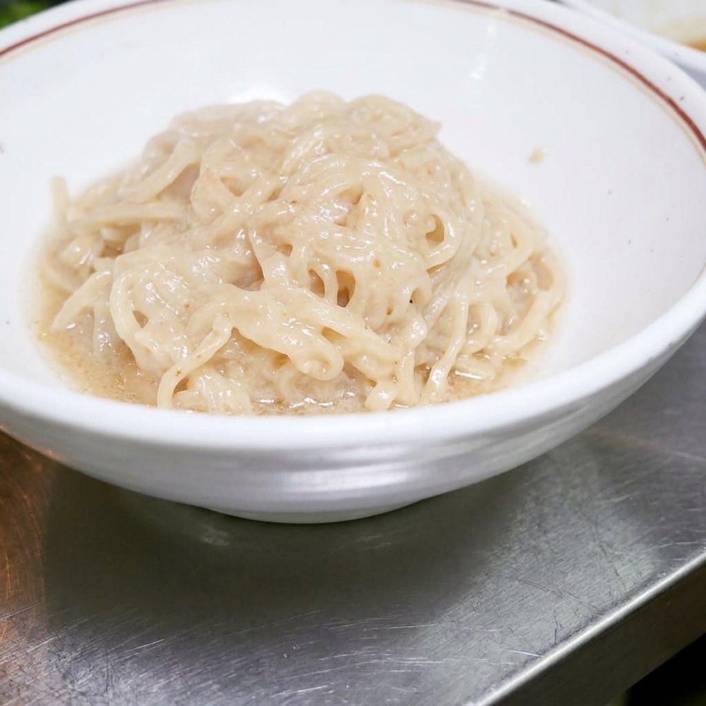 ソースと絡める準備ができた、白い丼の中にきれいに収まっている茹でたラーメンの麺。