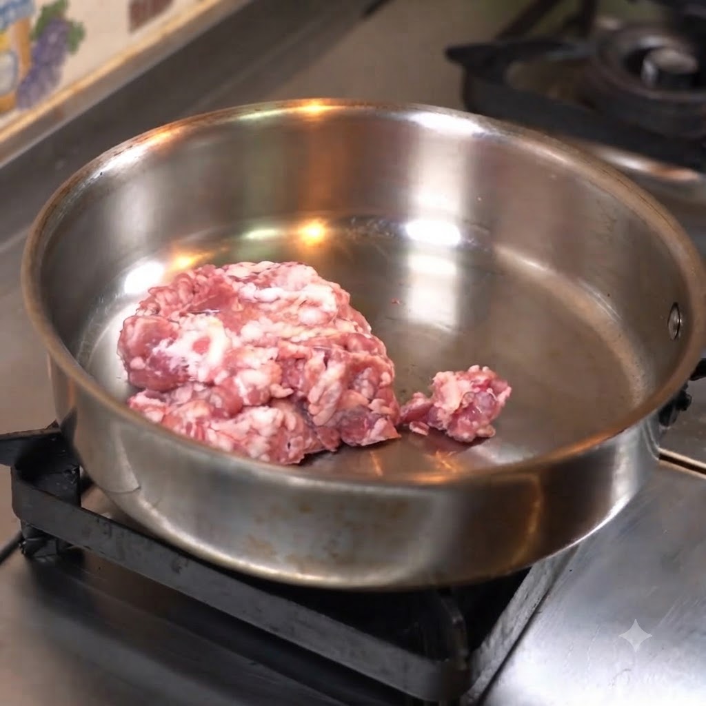 フライパンに広げた豚ひき肉を押し付けるようにして焼いている様子