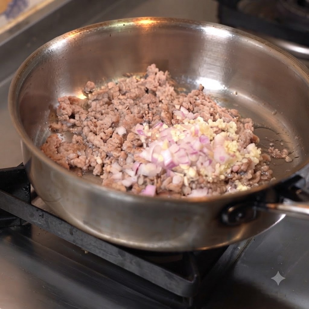 フライパンでひき肉と刻んだにんにく、玉ねぎを一緒に炒め合わせている様子