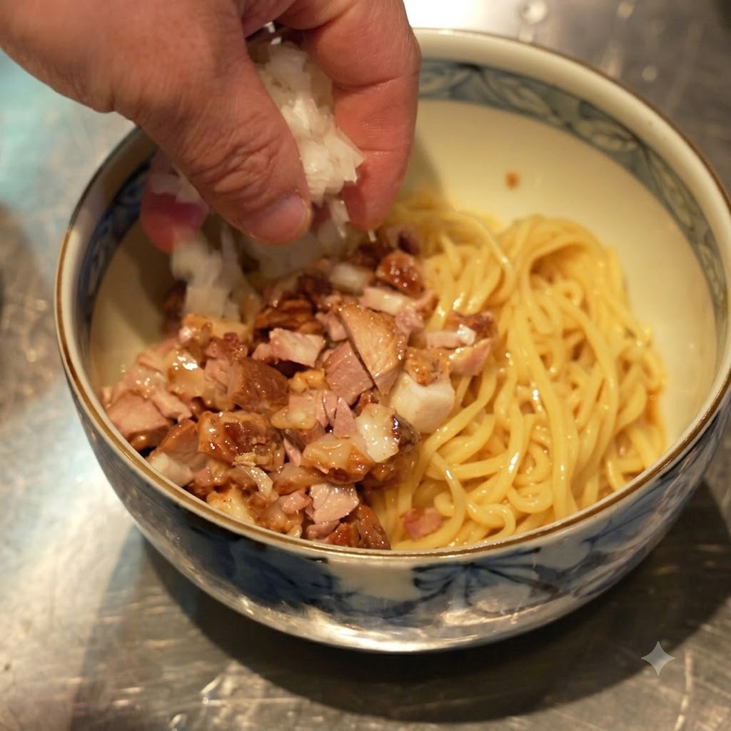 麺と刻みチャーシューの入った丼に、手で刻んだ白玉ねぎが振りかけられている様子。