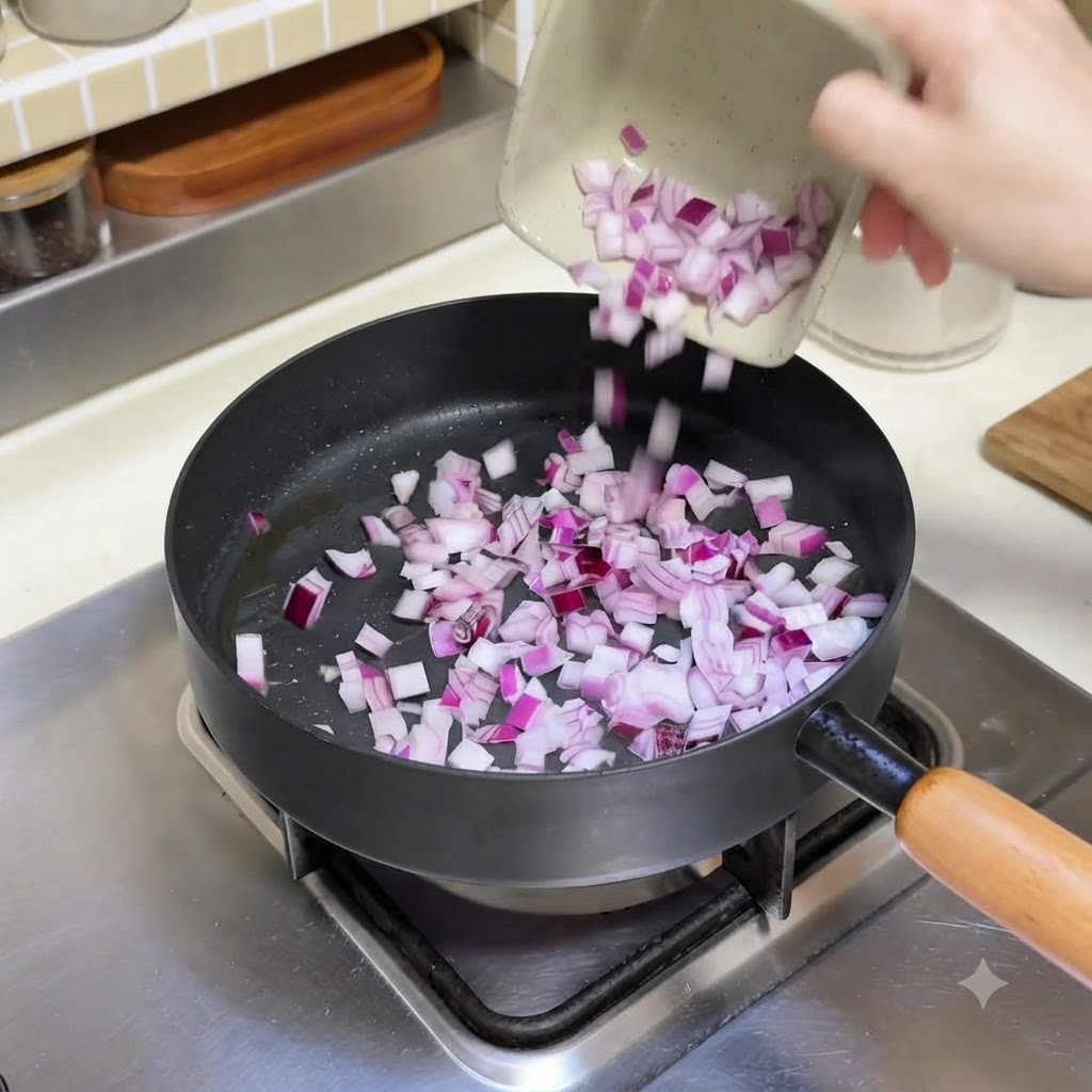 小さな器に入ったみじん切りの赤玉ねぎを、油を熱したフライパンに投入している様子。