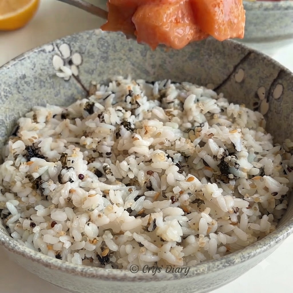 白米と刻み海苔が入った陶器の丼に、スプーンですくったサーモンの具材を盛り付けている様子。