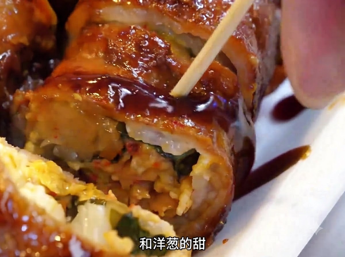 ヘラを使って熱々の鉄板の上で肉巻きを裏返している様子。