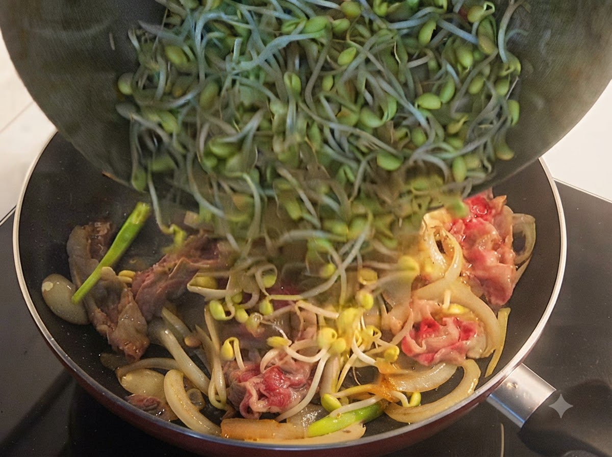軽く火が通った牛肉と玉ねぎが入ったフライパンに、ボウルから新鮮な豆もやしをたっぷり注ぎ入れている様子。