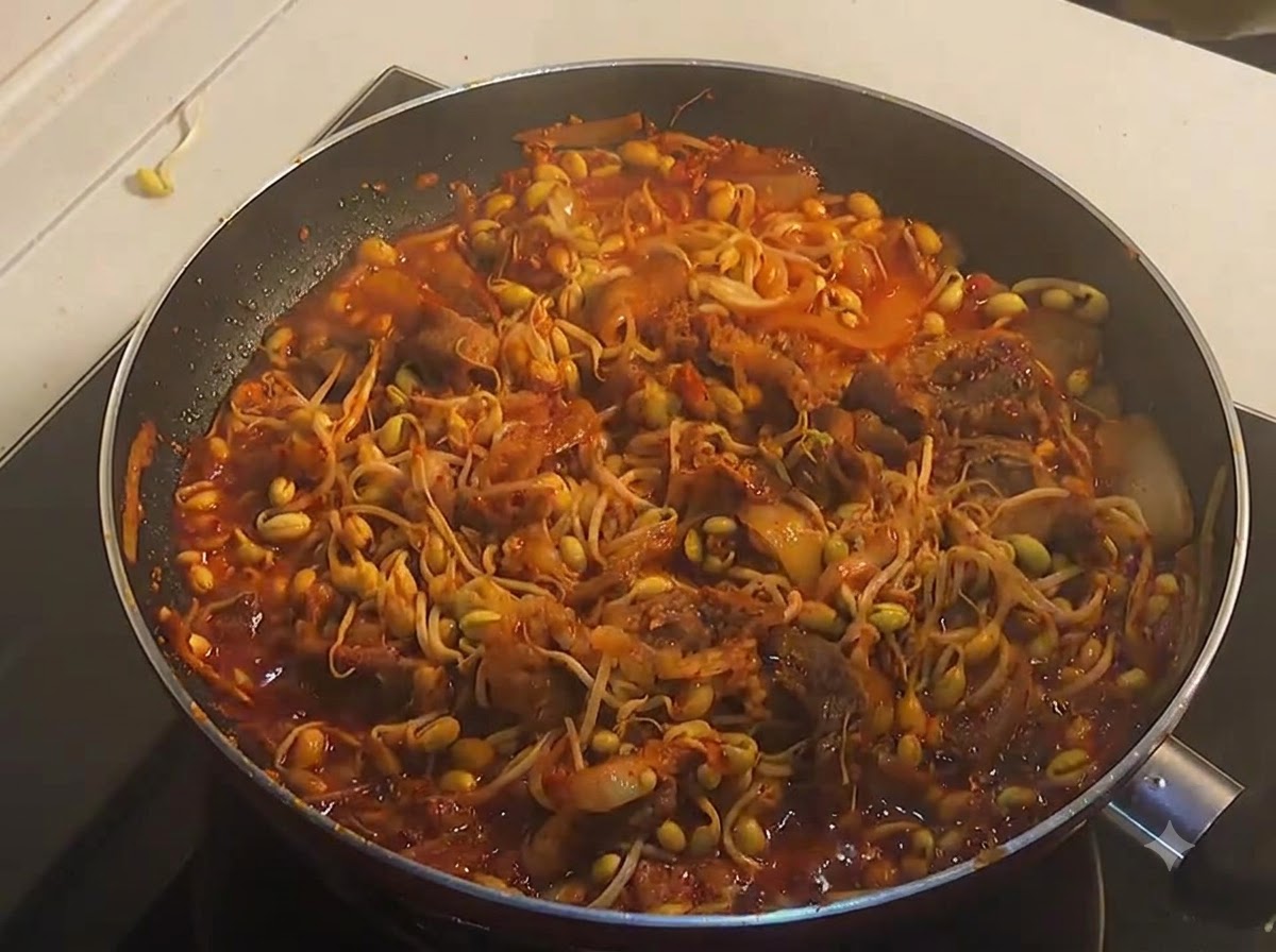 フライパンの中で、旨辛い牛肉と豆もやしが赤いソースと絡んでグツグツと煮立っている様子。