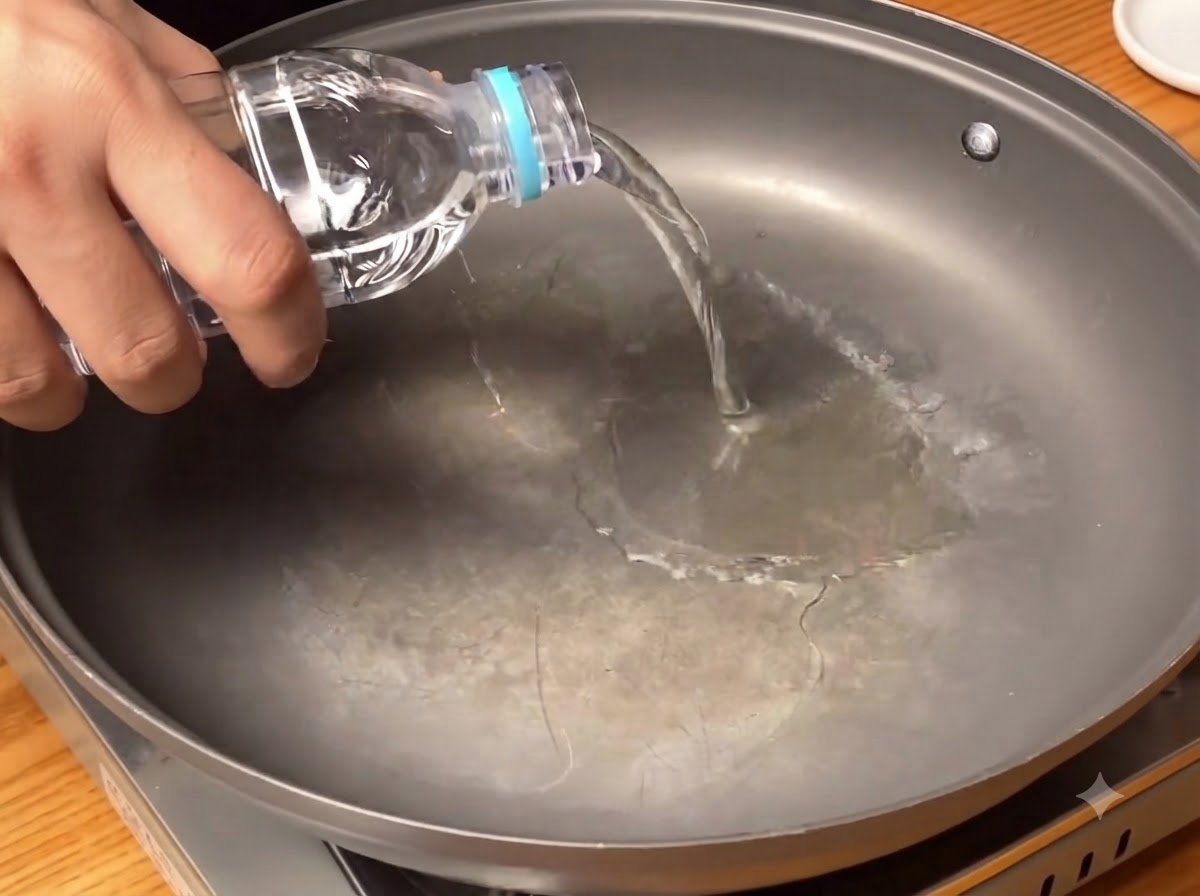 広めの調理用鍋の底に、ボトルからきれいな水が注がれている様子。