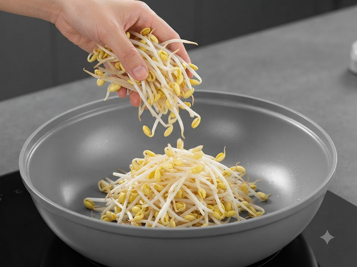 手から鍋の中心へと落とし入れられる新鮮な大豆もやし。