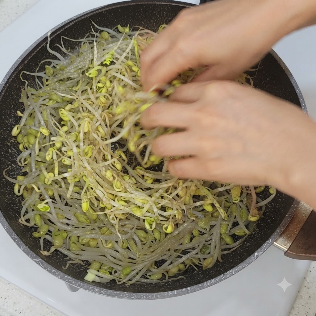 もやしの上に、野菜と豚バラ肉のスライスがフライパンに並べられている様子。