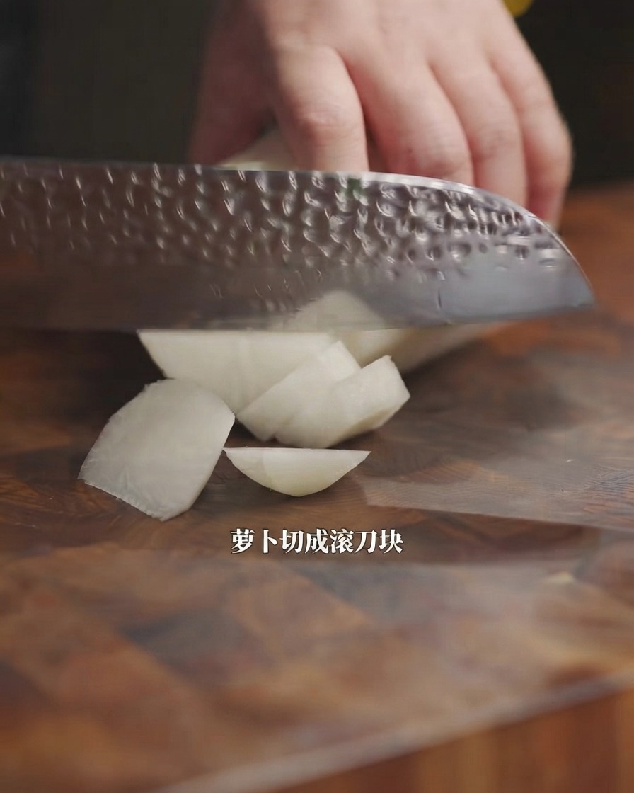 木製のまな板の上で、包丁を使って白大根を乱切りにしている様子。