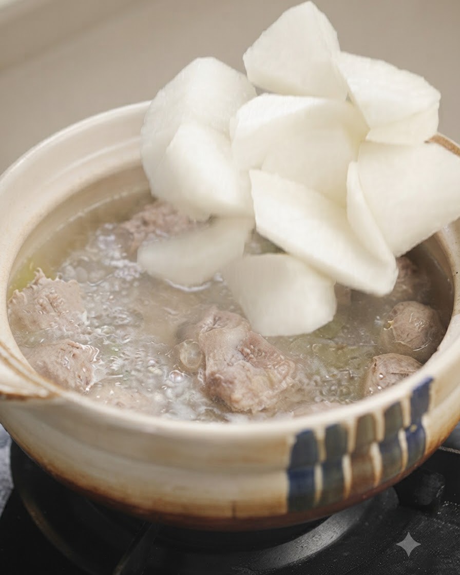 グツグツと煮えるスープの中に、白大根の塊を入れている様子。