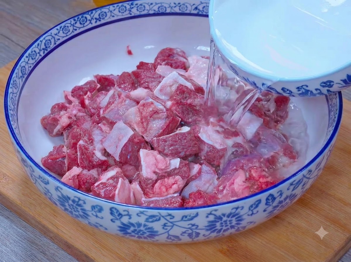ボウルから水が注がれ、塩と酢の混合液に牛肉の塊が浸されている様子。