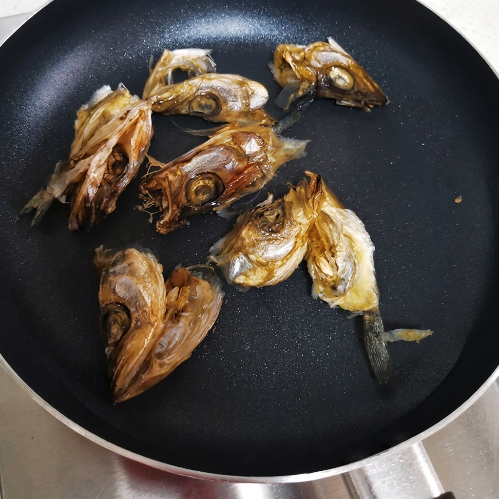 冷水を入れた平鍋に干し魚の頭が並べられ、加熱の準備ができている状態。