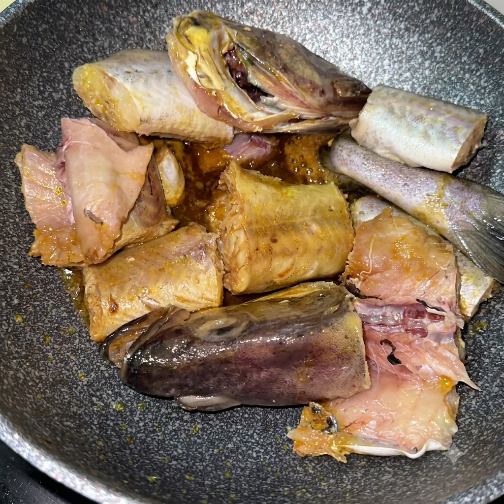 スライスした黄色いジャガイモと一緒に、鍋でタラの切り身が焼かれている状態。