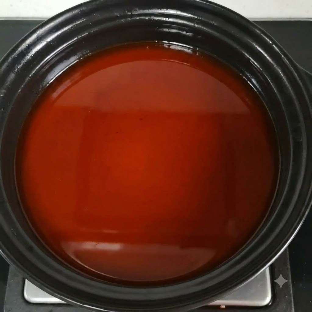 鍋の中の赤褐色のスープに魚醤を混ぜ合わせている様子。