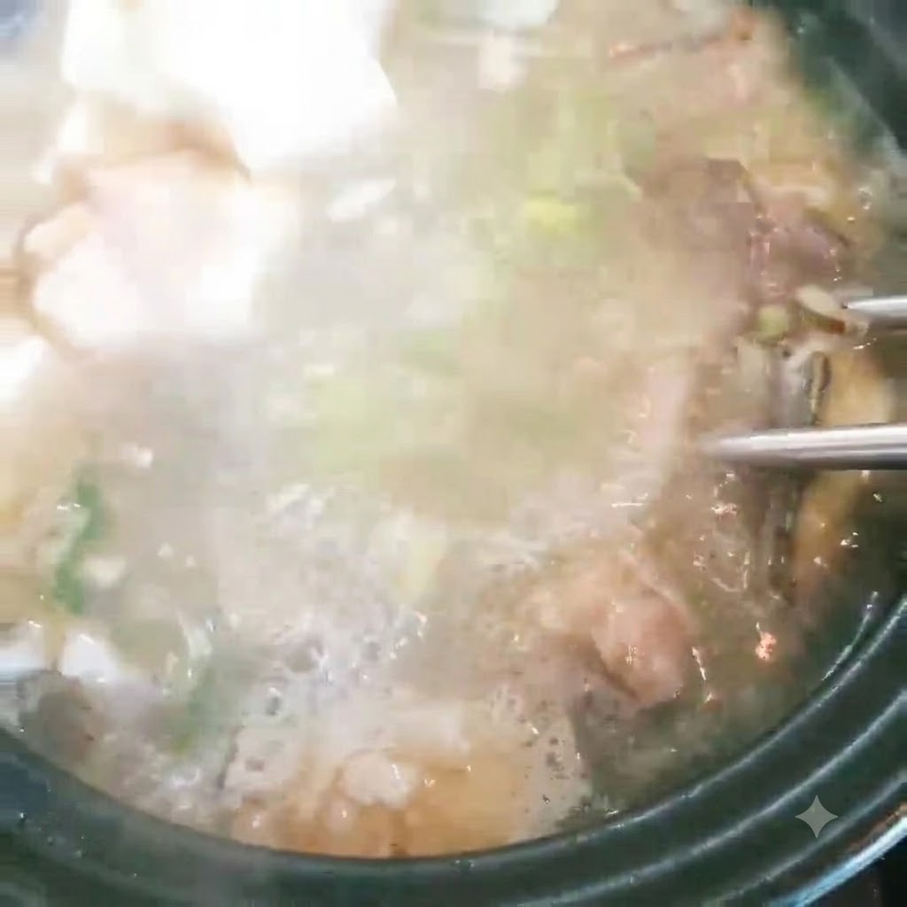 豆腐块被加入到带有葱花并正冒着泡的鱼汤锅中。