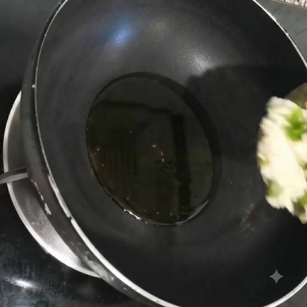 黒い中華鍋の中で、細かく刻んだ長ねぎ、にんにく、パクチーが熱した油でジュージューと炒められている様子。
