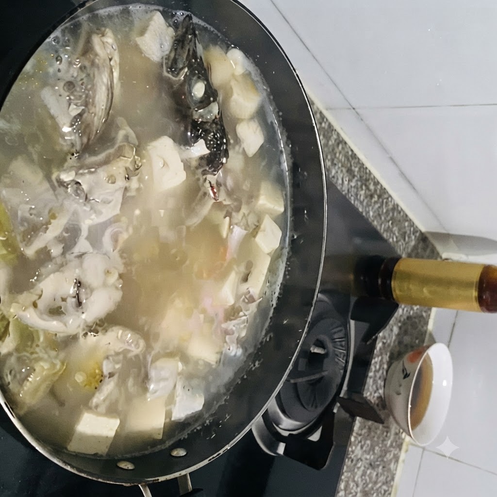 グツグツと煮える豆腐入りの魚のスープに、調味料を加え入れている様子。