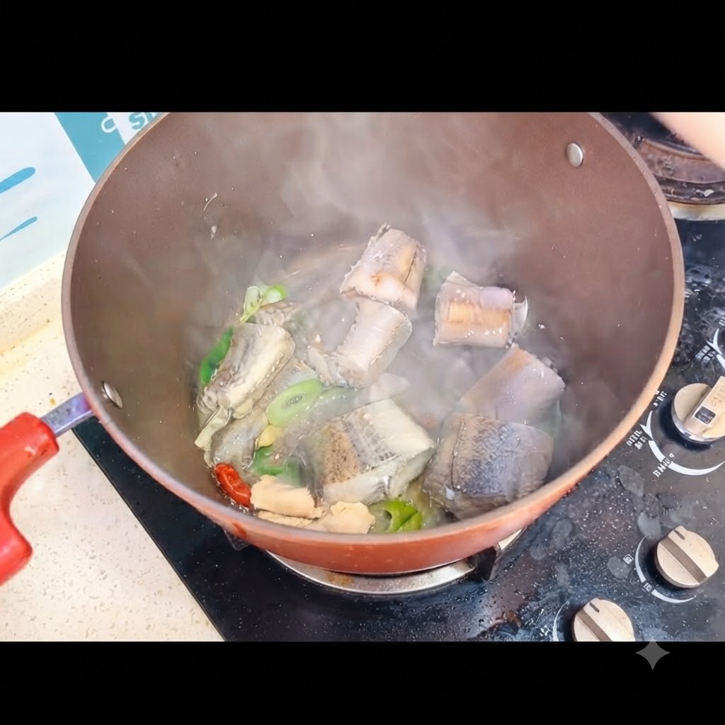 コンロの上の鍋に入った魚の切り身に、熱湯を注ぎ入れているところ。