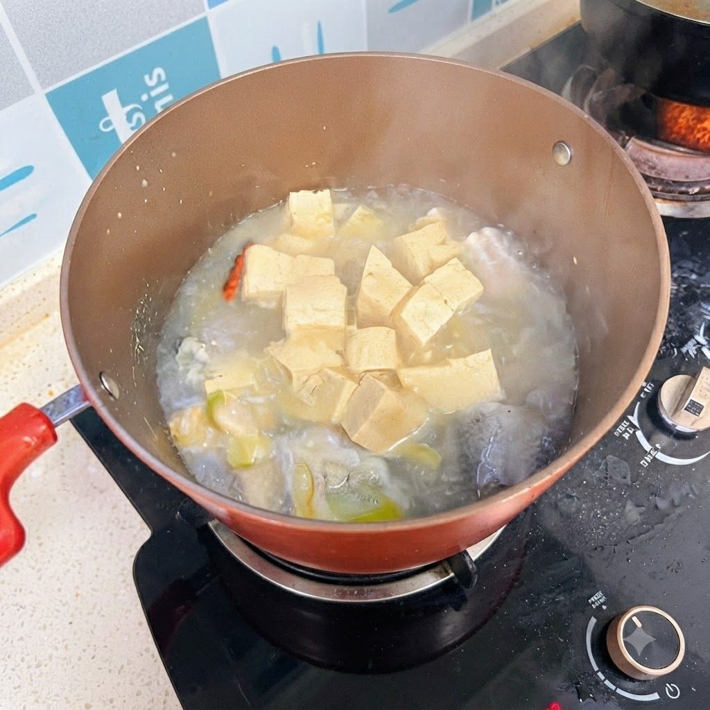 スープが乳白色になり、コンロの上でグツグツと煮込まれている魚と豆腐のスープの鍋。