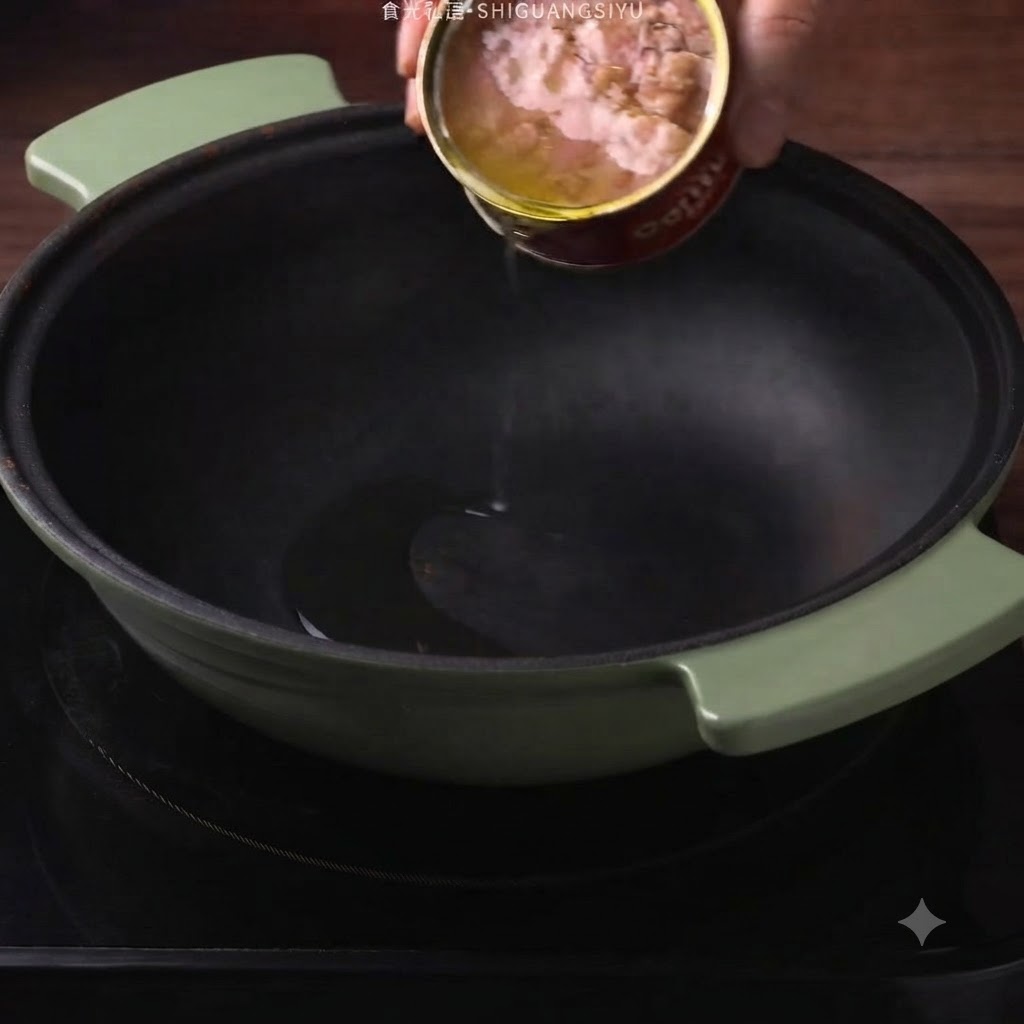 緑色の鍋に、缶詰からツナの旨味オイルが注がれている様子