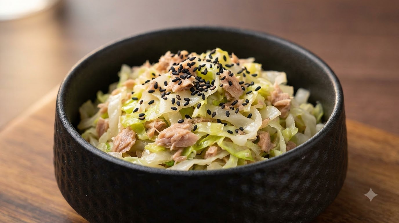黒ごまをトッピングした、ツナの旨味が染み込んだキャベツの煮物が入った小さな黒いお椀