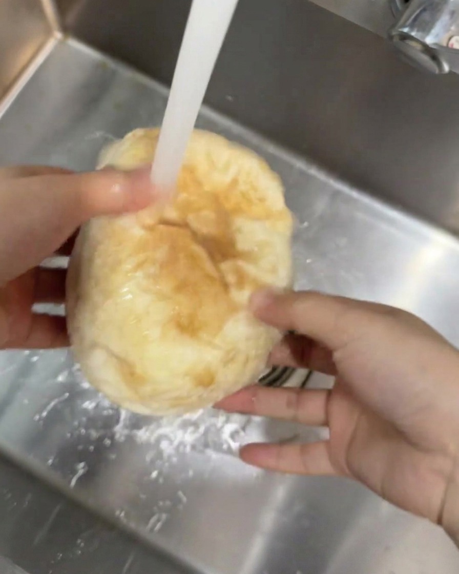 キッチンのシンクで流水の下に置かれた丸いチバッタパン。