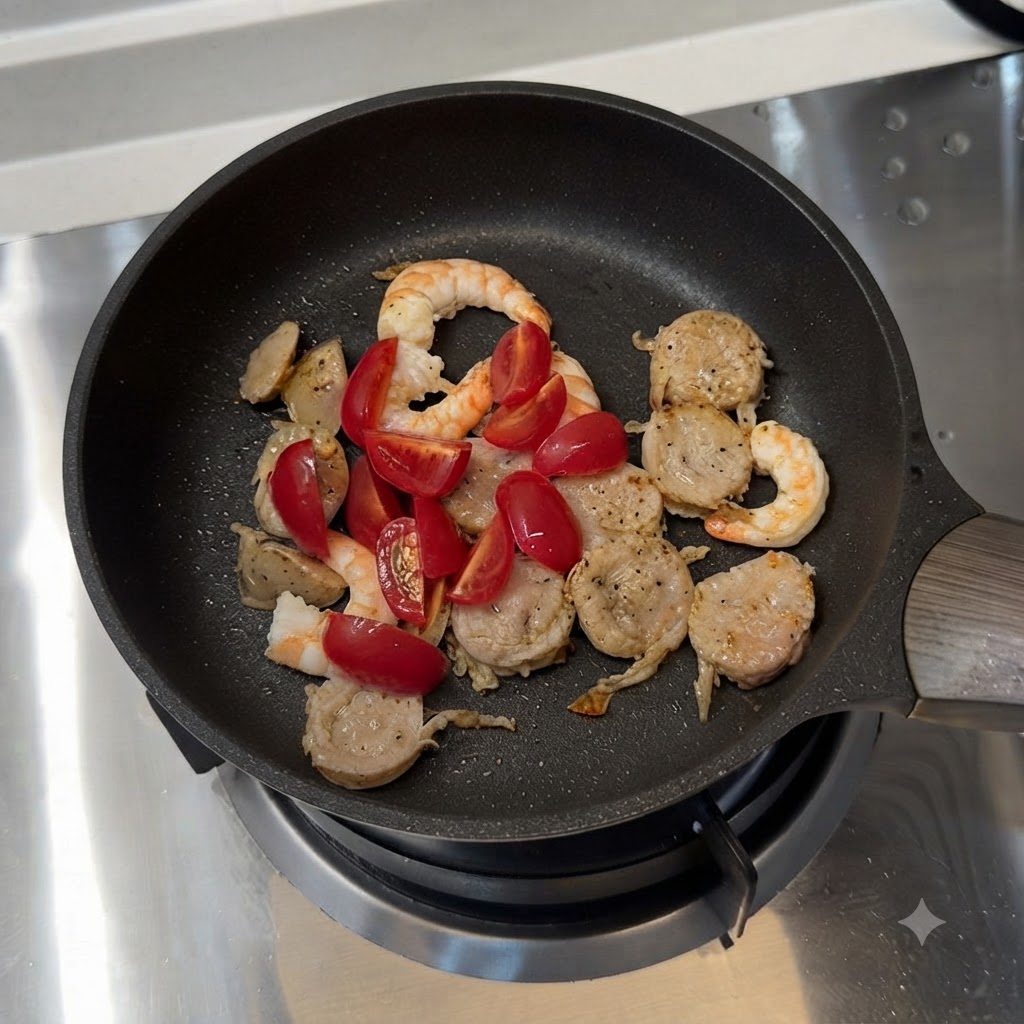 ミニトマトとスライスしたピーマンがソーセージやエビと混ざり合っているフライパン。