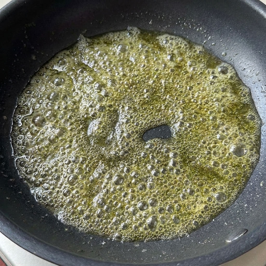 フライパンの中で溶けたバターの中に、薄口醤油とトマトペーストが加えられている様子