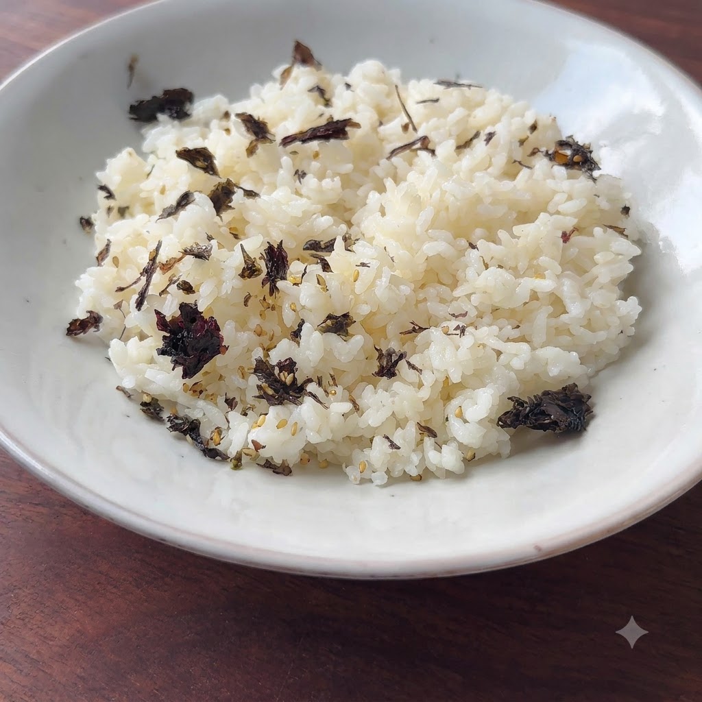 ダークなフレークがトッピングされた味付けご飯が白いボウルに入り、盛り付けの準備ができている様子