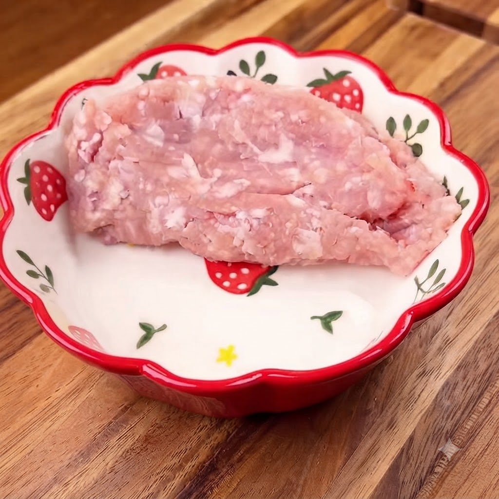 模様入りのボウルに入れられた細切りの豚肉と、その上に乗せられた刻みネギ。